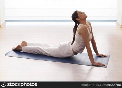 Young woman doing yogic &rsquo;sun salutation&rsquo; on mat