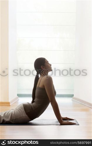 Young woman doing yogic &rsquo;sun salutation&rsquo; on mat