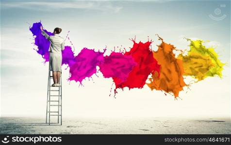 Young woman drawing splashes. Young woman standing on ladder drawing splashes with finger