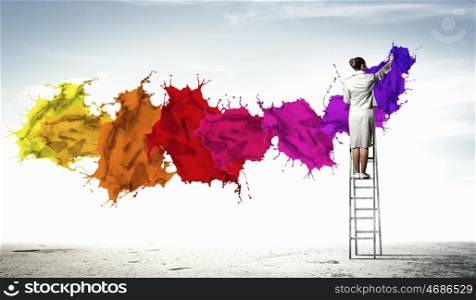 Young woman drawing splashes. Young woman standing on ladder drawing splashes with finger