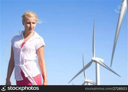 young woman dreams about the future on a wind farm beneath eolic generator