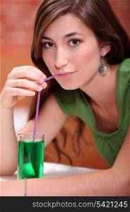 young woman dressed in green drinking a lemonade and mint cordial with a drinking straw
