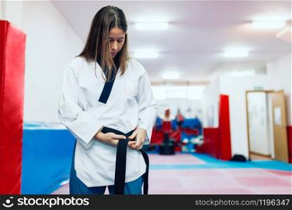 Young woman dresses in her taekwondo suit in front of the mirror