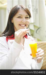 young woman drink juice outdoor in bright restaurant garden at spring