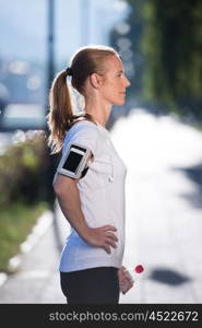 young woman drinking a water after mornig jogging workout city sunrise in background