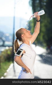 young woman drinking a water after mornig jogging workout city sunrise in background