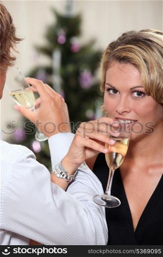 Young woman drinking champagne with her boyfriend at Christmas