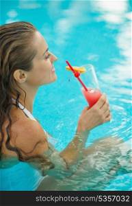 Young woman drinking cocktail in pool