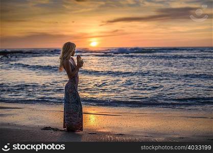 Young woman drinking cocktail on beach at sunset, Tamarindo, Costa Rica