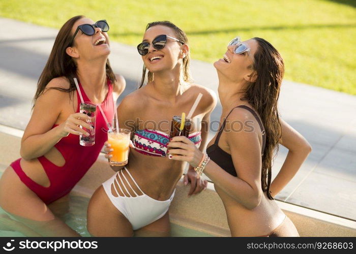 Young woman  drinking coctail and having fun by the pool at hot summer day