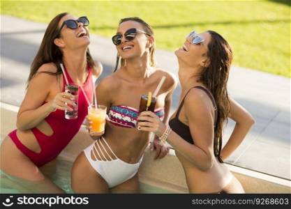 Young woman  drinking coctail and having fun by the pool at hot summer day