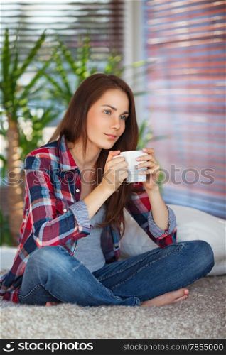 Young woman drinking coffee / tea on sofa at home