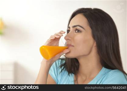 Young woman drinking glass of fresh orange juice at home