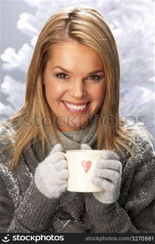 Young Woman Drinking Hot Drink Wearing Knitwear In Studio In Front Of Christmas Tree