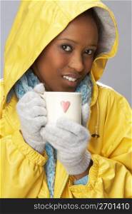 Young Woman Drinking Hot Drink Wearing Yellow Raincaot