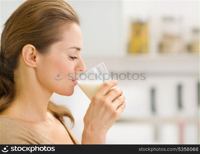 Young woman drinking milk in kitchen