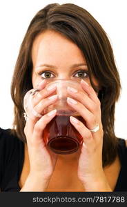 Young woman drinking tea from a glass, holding it comfortably with two hands