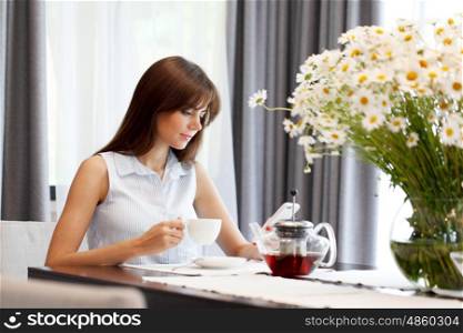 young woman drinking tea. young woman drinking tea and looking at her phone