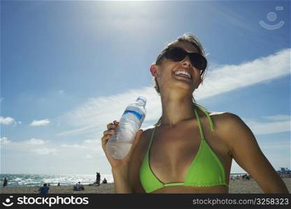 Young woman drinking water on beach
