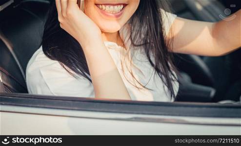 Young woman driving the car and talking on the phone while driving. sun shines through front window. Blurred background and Soft focus.