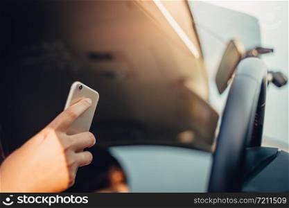 Young woman driving the car and use the phone while driving. sun shines through front window. sun shines through front window. Blurred background and Soft focus.