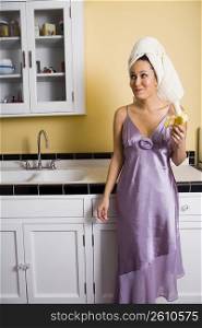 Young woman eating banana in kitchen