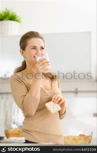 Young woman eating crisp bread with milk