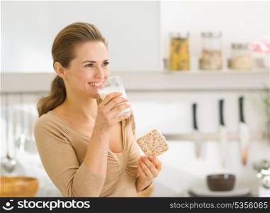 Young woman eating crisp bread with milk and looking on copy space