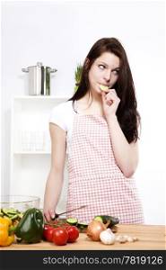 young woman eating cucumber. young woman eating cucumber while preparing salad