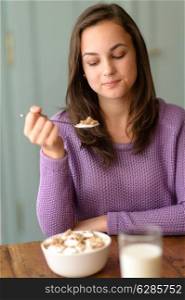 Young woman eating healthy cereal breakfast looking down