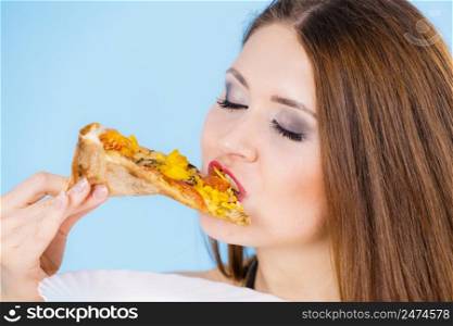 Young woman eating hot fresh pizza slice, on blue. Delicious fast food meal. People, italian cuisine concept.. Woman eating hot pizza slice