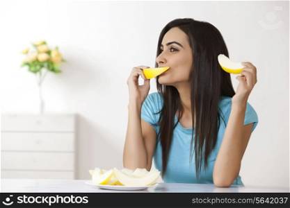 Young woman eating melon at home