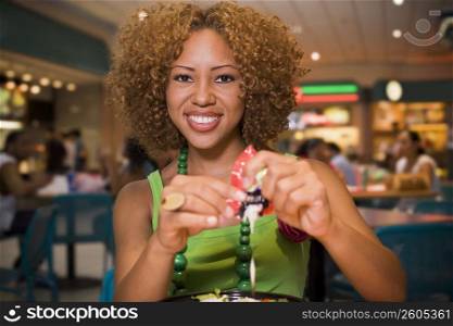 Young woman eating salad in mall food court