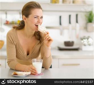 Young woman eating snacks in modern kitchen