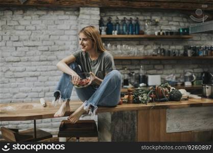 Young woman  eating vegan meal and detox food in the rustic kitchen