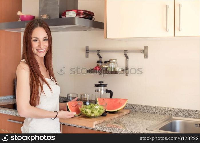 Young woman eating watermelon in the kitchen