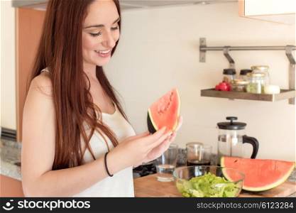 Young woman eating watermelon in the kitchen