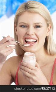Young Woman Eating Yoghurt In Studio