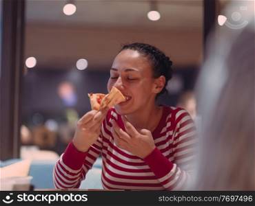 Young woman eats a pizza from delivery service while at work at the modern office in late night . Young woman eats a pizza from delivery service at office