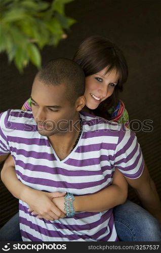 Young woman embracing a young man from behind and smiling
