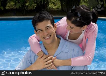 Young woman embracing a young man from behind and smiling