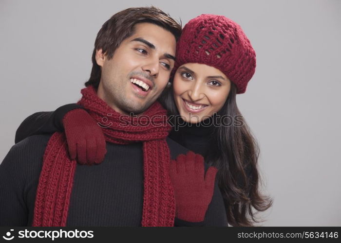 Young woman embracing her boyfriend over grey background