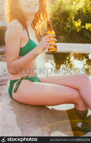Young woman enjoying a beer in a summer party