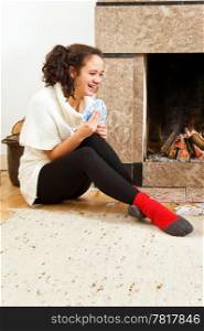 Young woman enjoying a cosy game of cards by the warmth of a fireplace