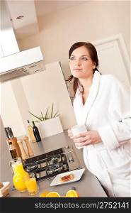 Young woman enjoying coffee and breakfast in modern kitchen