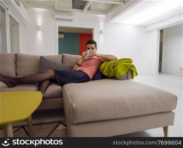 young woman enjoying free time drinking tea while relaxing on corner sofa at big stylish duplex apartment