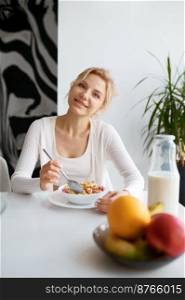 Young woman enjoying healthy breakfast on home kitchen. Attractive slim girl eating bowl of cereal homemade food. Young woman enjoying healthy breakfast on home kitchen