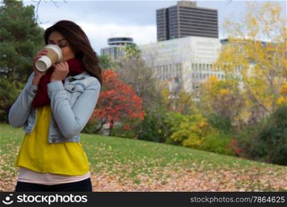 Young woman enjoying her beverage outdoors during fall