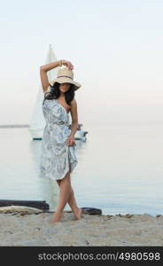 Young woman enjoying morning on tropical beach with yacht on background