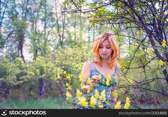 Young woman enjoying spring flower among blossoming trees.. Young woman in the spring garden